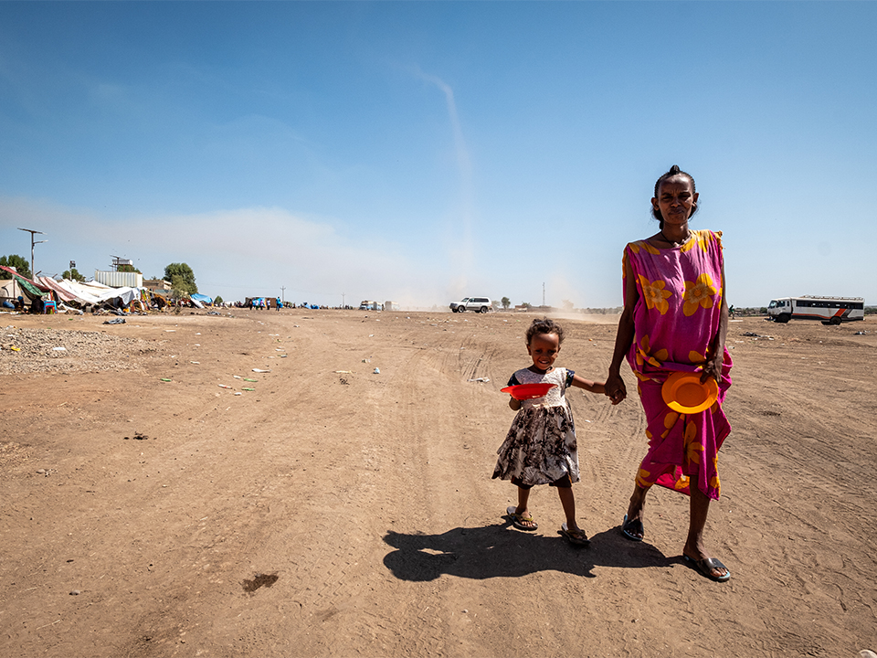 Moeder en dochter, vluchtelingen uit Tigray, lopen met lege bordjes naar voedseldistributie in Gedaref, Sudan kopiëren